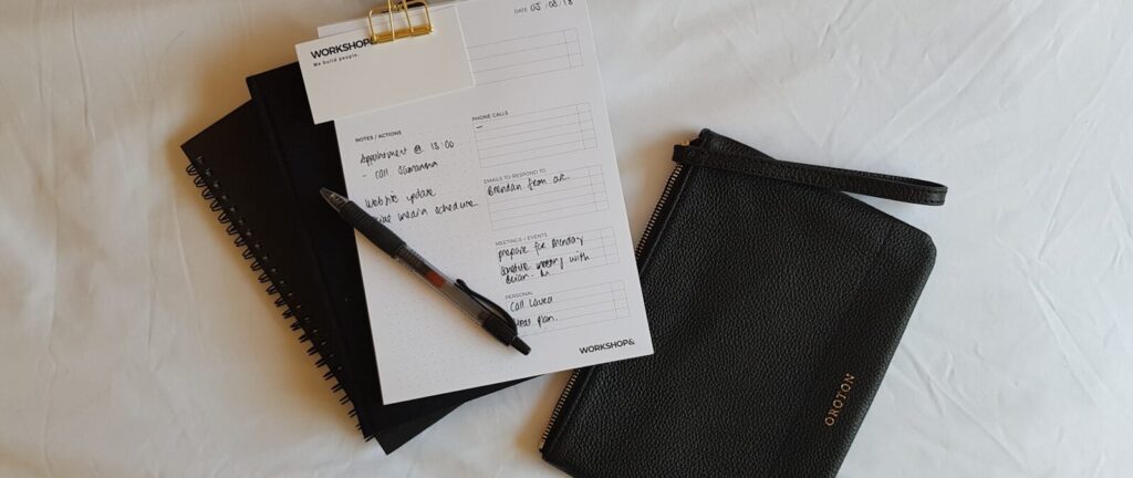 a notepad, pen, and notebook on a bed