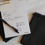 a notepad, pen, and notebook on a bed