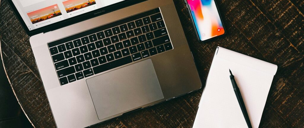 MacBook beside iPhone X on brown table