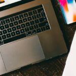 MacBook beside iPhone X on brown table